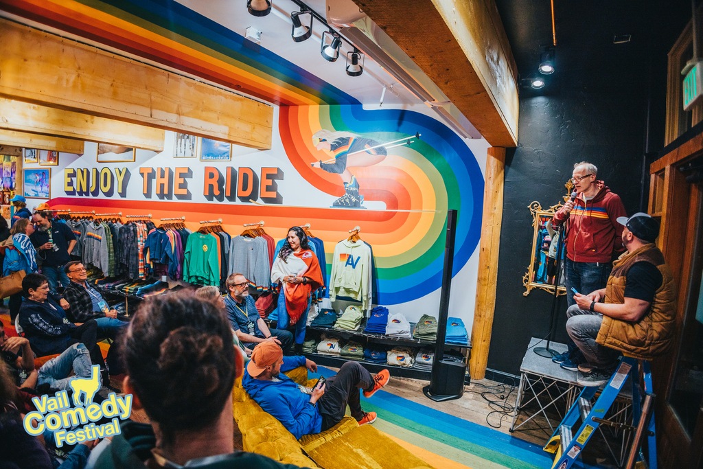 Mark Masters and Orin Be entertain an audience before a pop-up show at Aviator Nation.  Pictured is the infamous "high stage" and a ladder for comics to mount it at the 2022 Vail Comedy Festival.